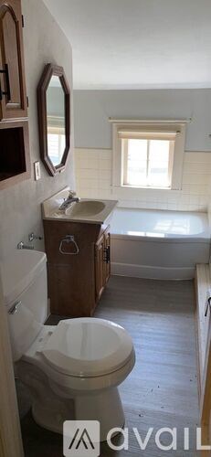 A bathroom with a toilet, sink, and mirror.