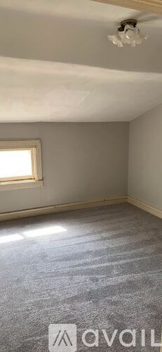 A room with a window and a carpeted floor.