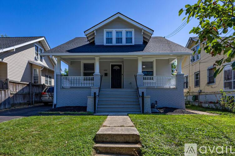 A house with a white front porch and a car parked in front.