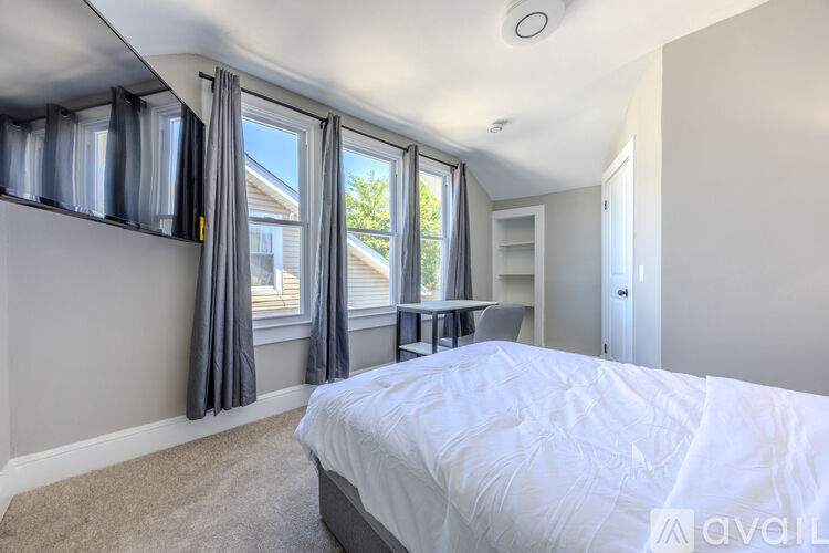 A bedroom with a large bed and a window with curtains.