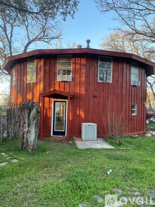 A red wooden house with a tree in front of it.