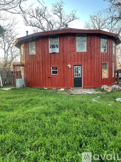 A red wooden house with a black door and windows.