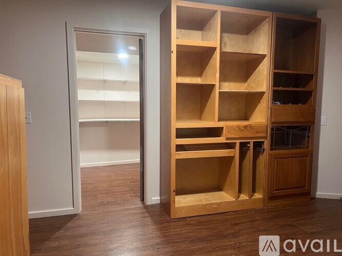 A room with a large wooden shelving unit and a doorway leading to another room.