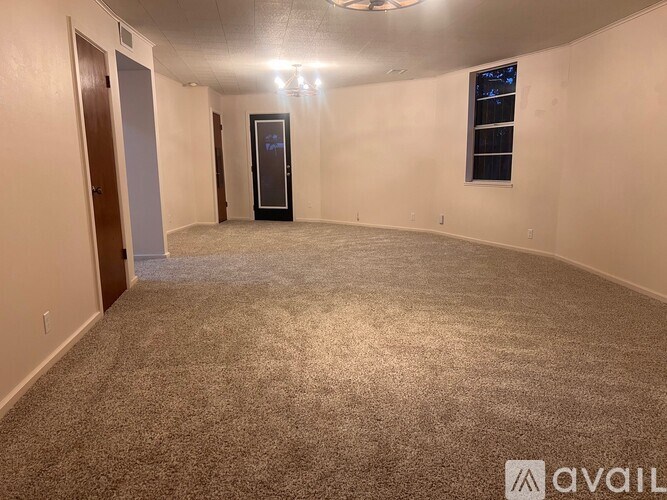 A room with a carpeted floor and a door on the left side.