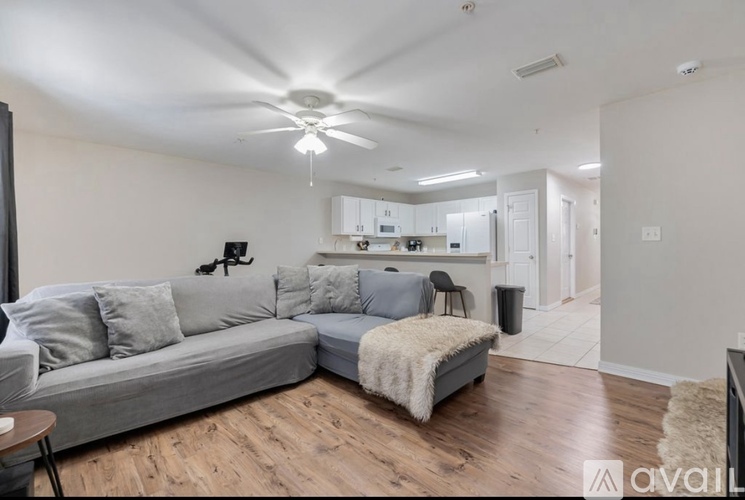A living room with a grey couch and a white ceiling fan.