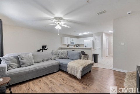 A living room with a grey couch and a white ceiling fan.