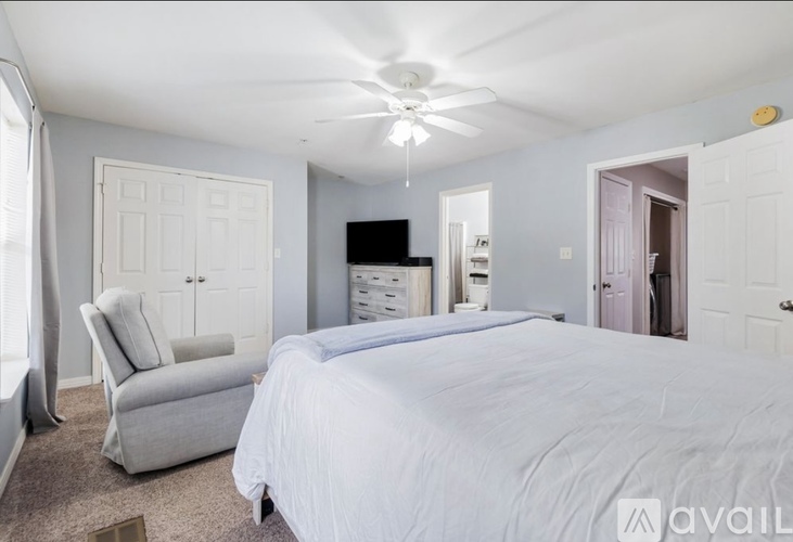 A bedroom with a large bed and a ceiling fan.
