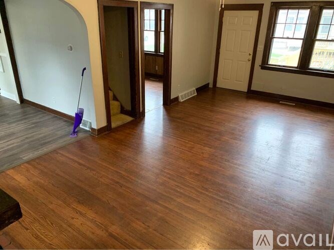 A room with wooden floors and a purple broom.