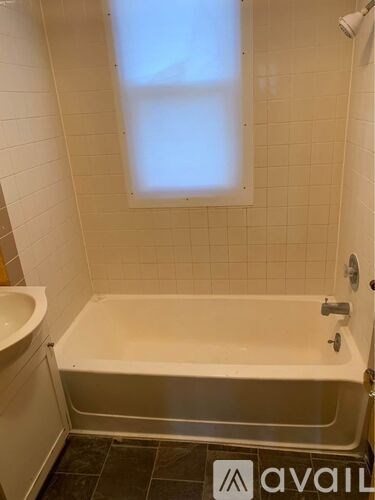 A white bathroom with a tub and a window.