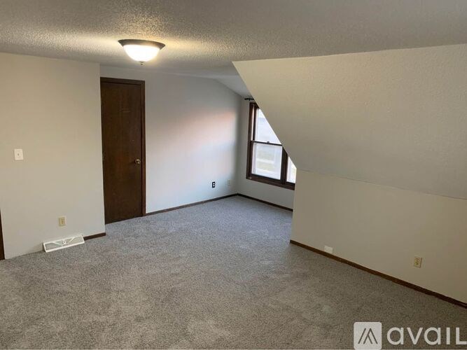 A room with a carpeted floor, a door, and a window.