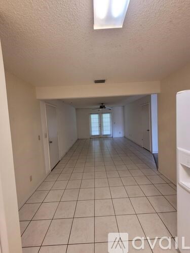 A long hallway with white tile floors and white walls.