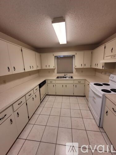 A kitchen with white cabinets and a white fridge.