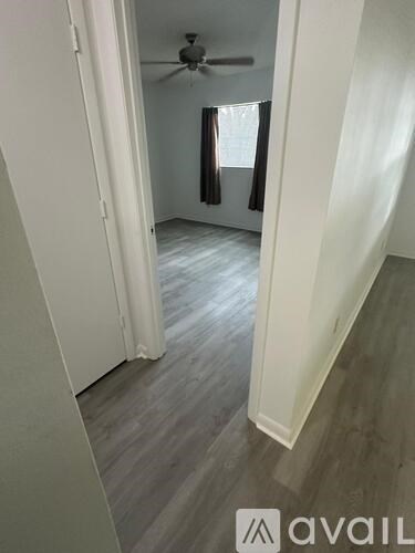 A room with a ceiling fan and light, and a window with curtains.