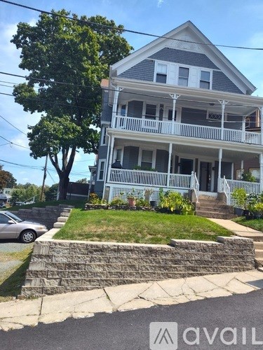 A two-story house with a porch and a car parked in front.