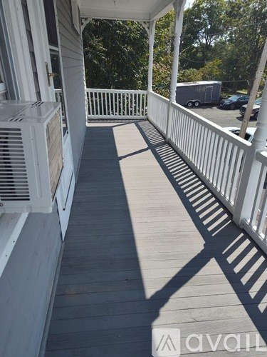 A porch with white railings and a wooden floor.