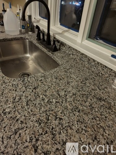 A kitchen countertop with a sink and a bottle.