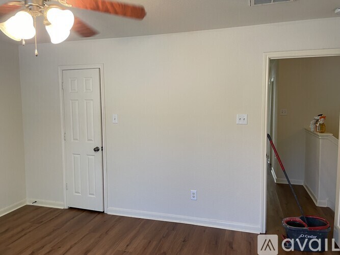 A room with a white door and a fan on the ceiling.