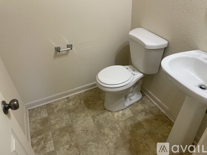 A bathroom with a toilet, sink, and tiled floor.