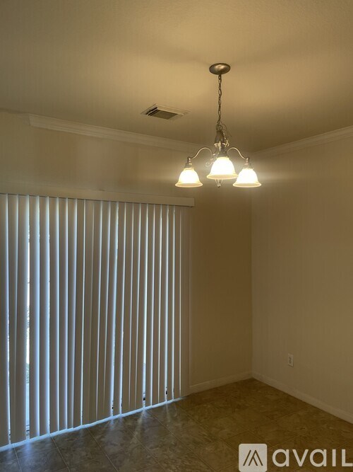 A room with a chandelier and a window with blinds.