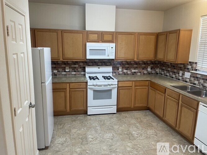 A kitchen with a white refrigerator, white stove, and brown cabinets.