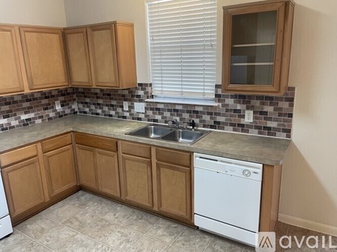 A kitchen with wooden cabinets and a white dishwasher.