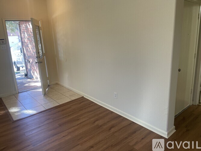 A room with white walls and wooden flooring, with a door on the left and another door on the right.