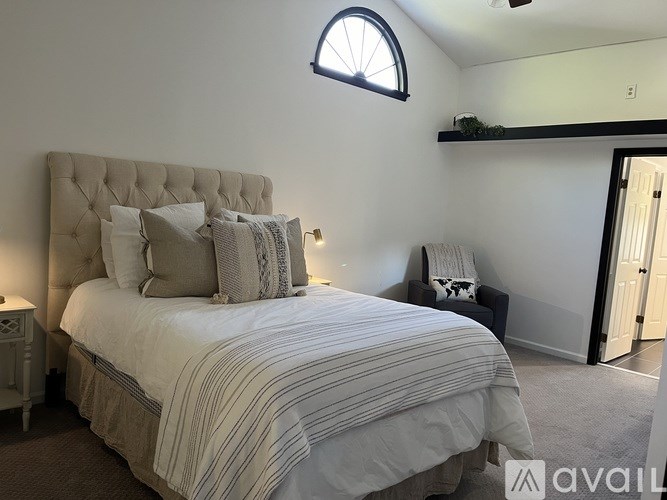 A bedroom with a large bed and a window above it.