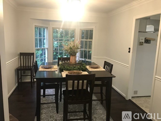 A dining room with a table set for two and a vase of flowers on the table.