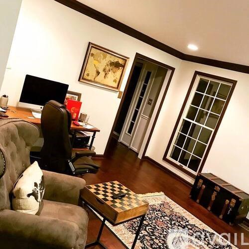A living room with a brown couch, a chair, a desk, and a computer.