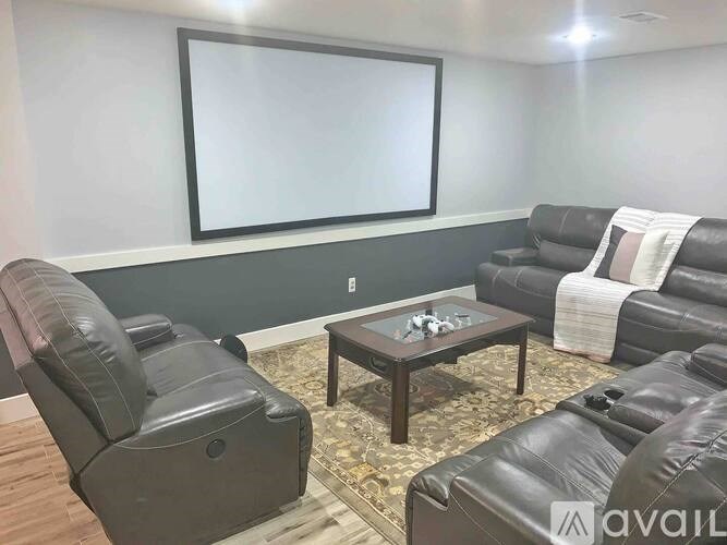 A living room with a large screen and comfortable seating.