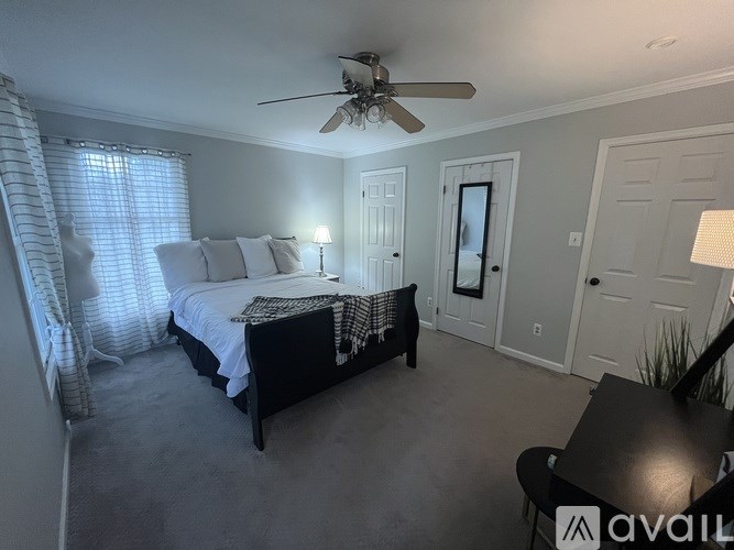 A bedroom with a bed, a ceiling fan, and a window with curtains.