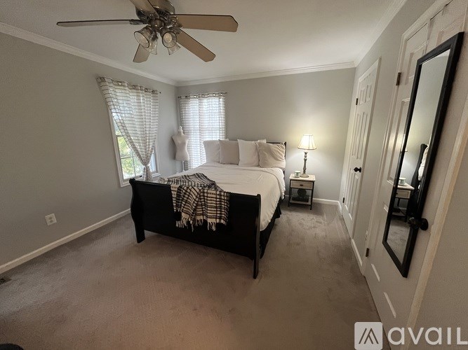 A bedroom with a bed, a ceiling fan, and a side table with a lamp.