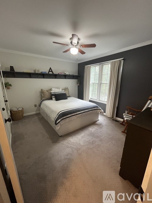 A bedroom with a bed, a dresser, and a ceiling fan.
