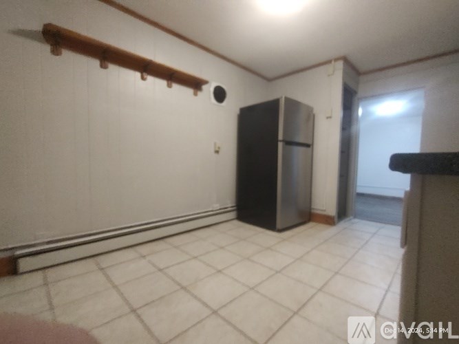 A kitchen with a black fridge and white tiles.