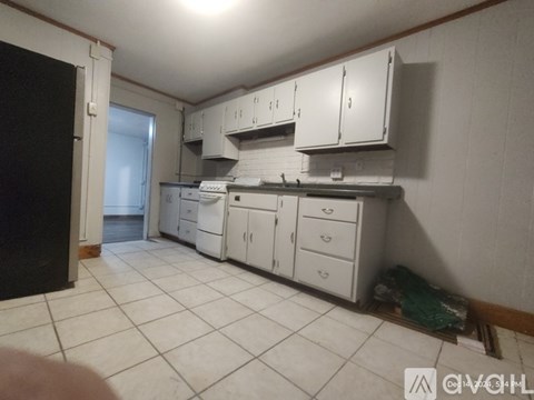 A kitchen with white cabinets and a black refrigerator.