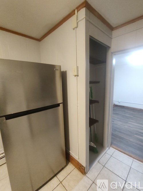 A stainless steel refrigerator sits in a kitchen next to a white door.