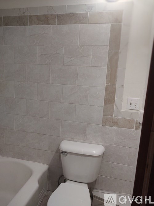 A white toilet in a bathroom with a tiled wall.