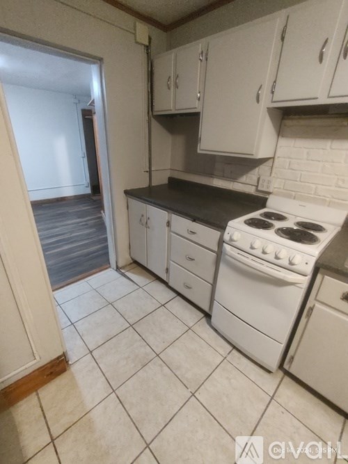A kitchen with a white stove and white cabinets.