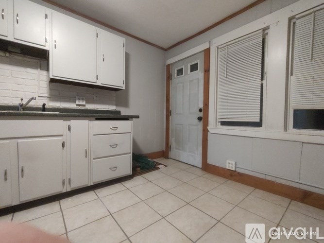 A kitchen with white cabinets and a white door.