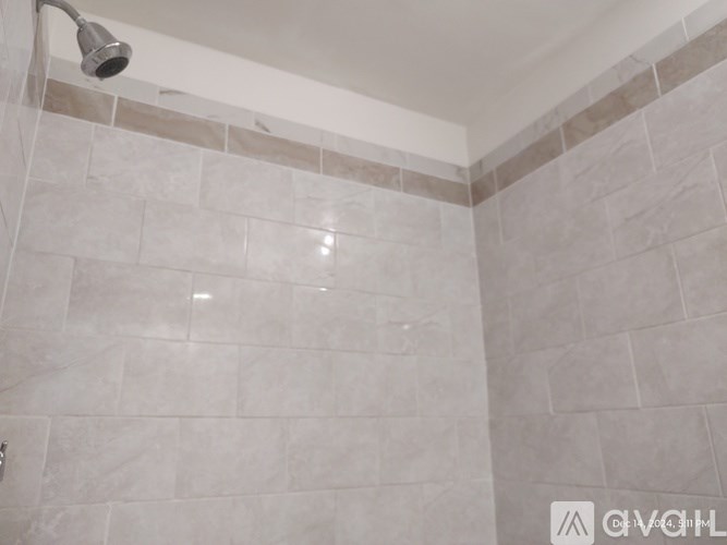 A shower head is mounted on a wall with tiled walls and floor.