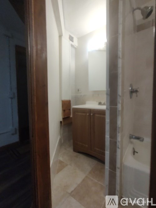 A bathroom with a shower, sink and cupboard.