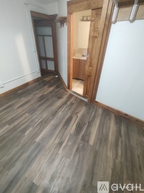 A room with wooden flooring and a doorway leading to another room.