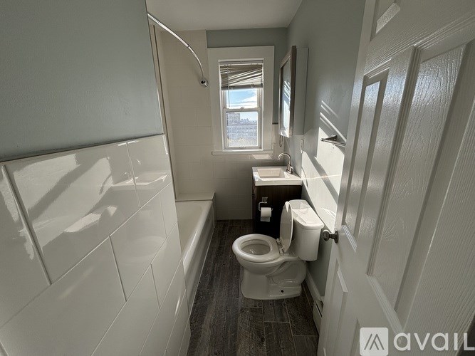 A bathroom with a toilet, sink, and a window.