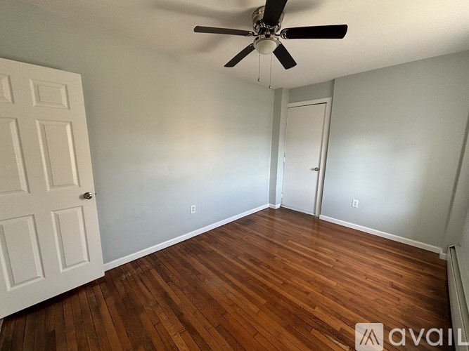 A room with a ceiling fan and wooden flooring.