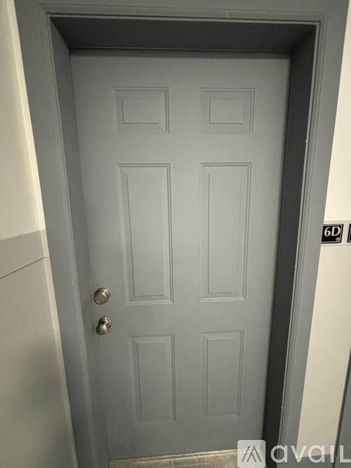 A white door with a silver handle and a black sign on the wall.