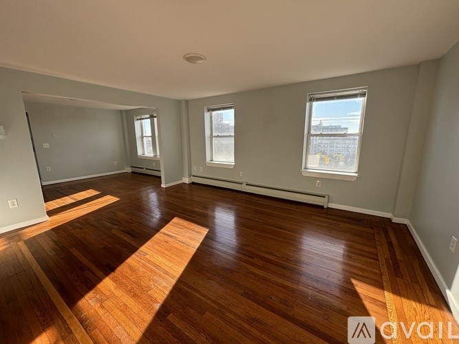 A room with wooden flooring and two windows.