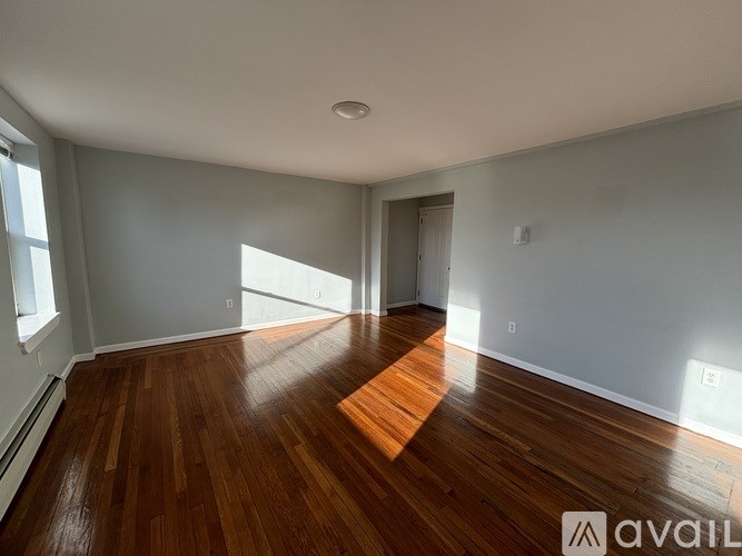 A room with wooden flooring and a door leading to another room.