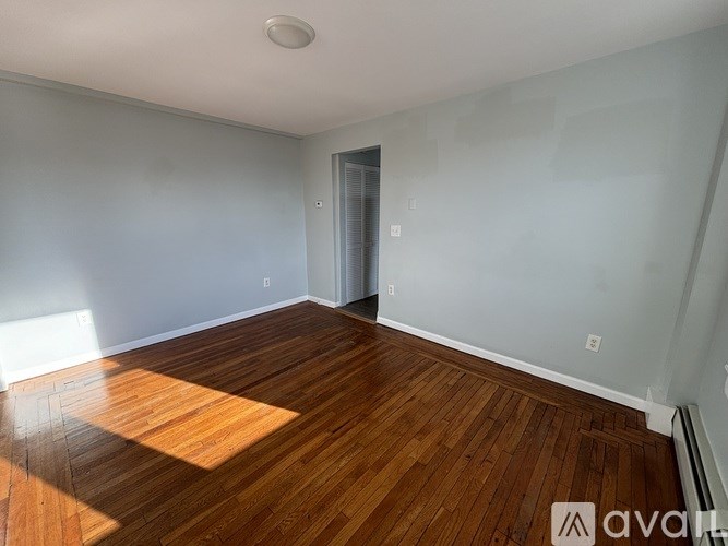 A room with wooden flooring and a door on the right side.