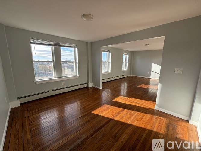 A spacious room with wooden floors and large windows.
