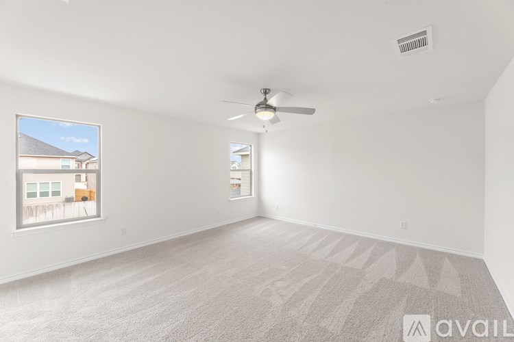 A spacious room with a carpeted floor and a ceiling fan.